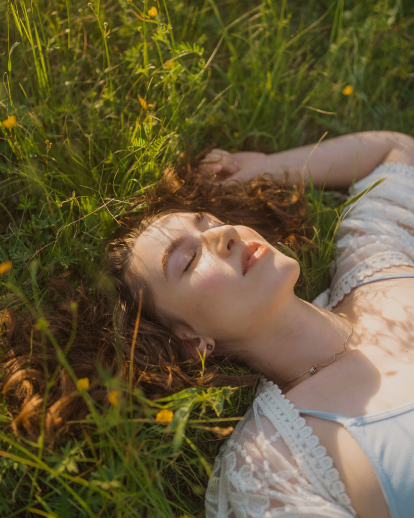 portrait of young woman laying in field of wildflowers
