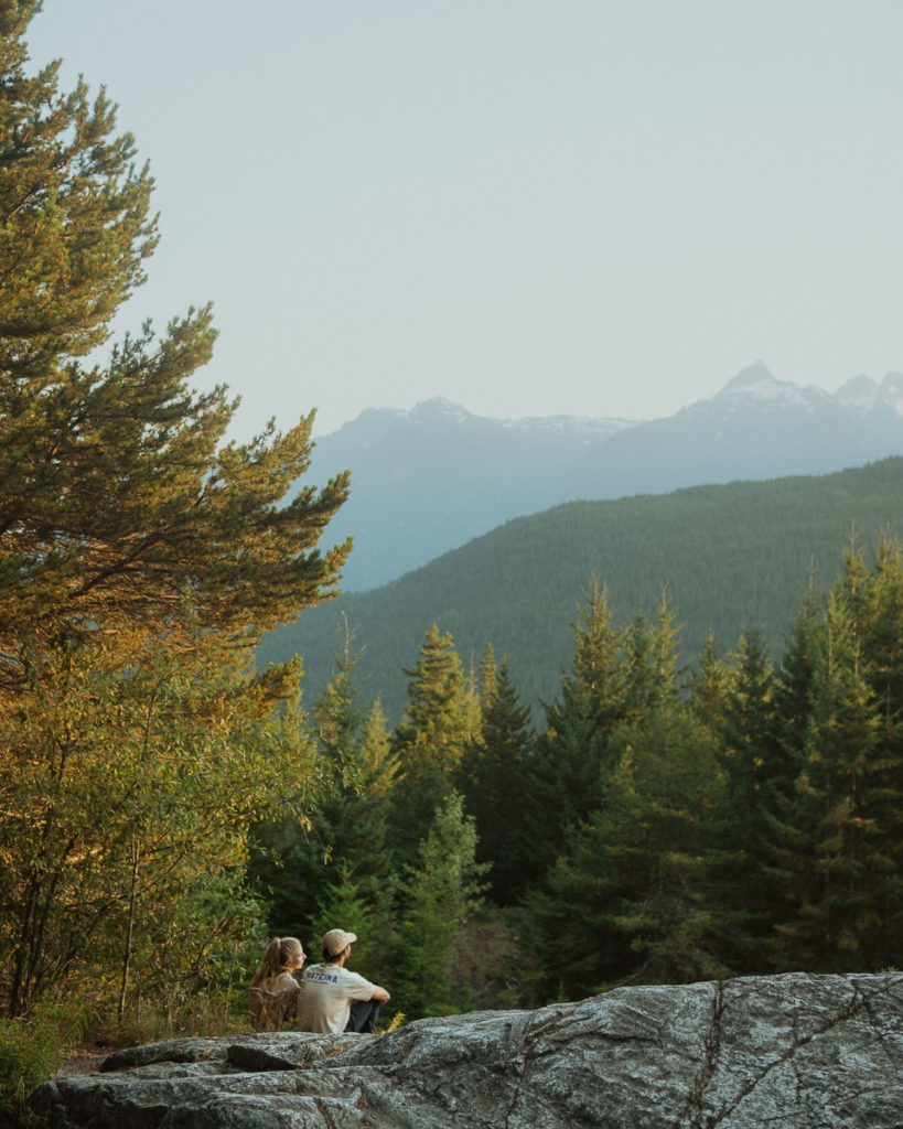 Young couple enjoying the view at a viewpoint location in Squamish British Colombia with mountains in the background
